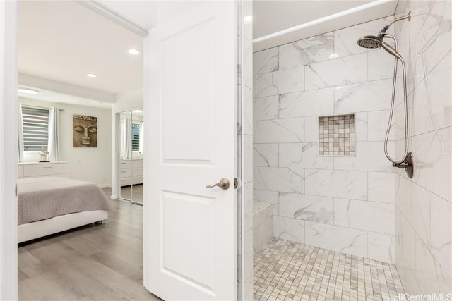 bathroom featuring a tile shower and wood-type flooring