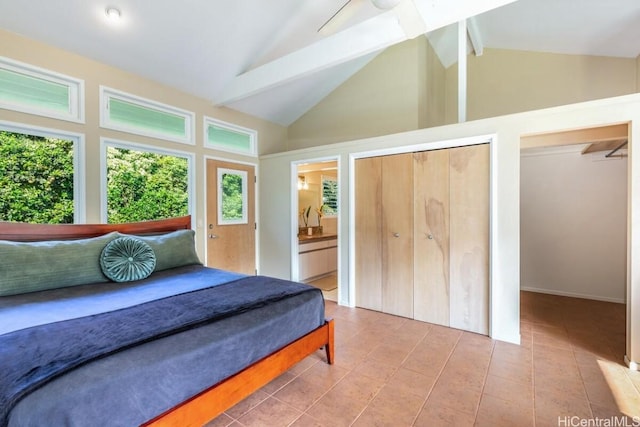 bedroom featuring connected bathroom, vaulted ceiling with beams, tile patterned floors, ceiling fan, and two closets