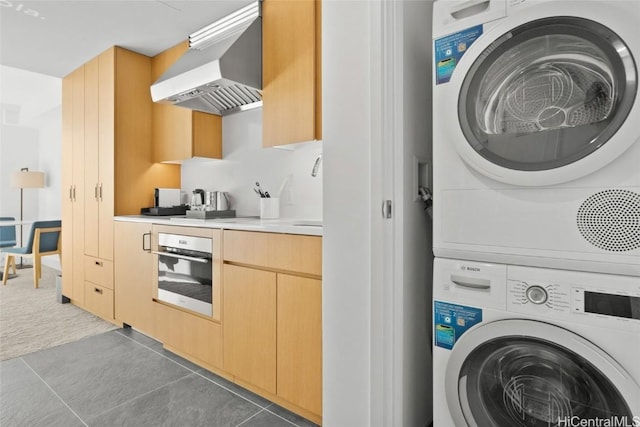 interior space featuring stacked washer and dryer and dark tile patterned flooring