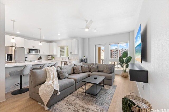 living room featuring sink, light wood-type flooring, and ceiling fan