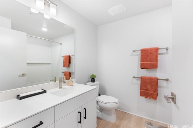 bathroom featuring toilet, vanity, hardwood / wood-style flooring, and walk in shower