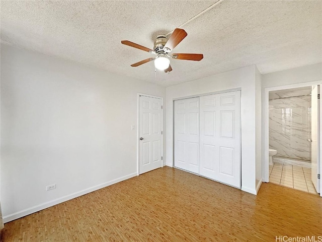 unfurnished bedroom with ceiling fan, connected bathroom, wood-type flooring, and a textured ceiling