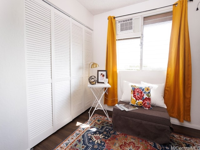 sitting room with a wall mounted air conditioner and dark hardwood / wood-style floors