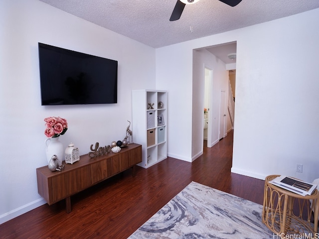 living room with a textured ceiling, ceiling fan, and dark hardwood / wood-style floors