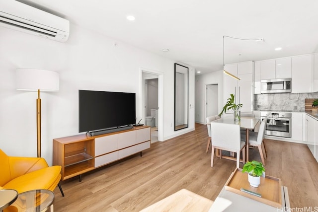 living room with a wall unit AC and light hardwood / wood-style floors