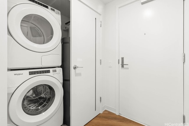 clothes washing area with stacked washer and dryer and wood-type flooring