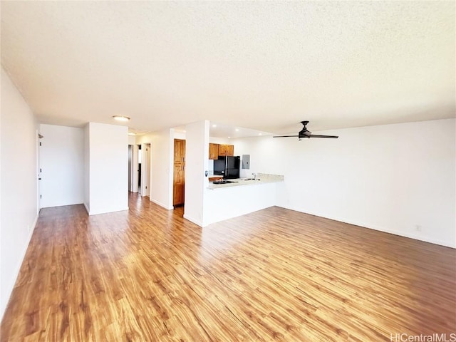 unfurnished living room featuring light hardwood / wood-style floors, ceiling fan, and a textured ceiling