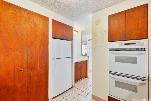 kitchen featuring white appliances, light tile patterned floors, and a textured ceiling