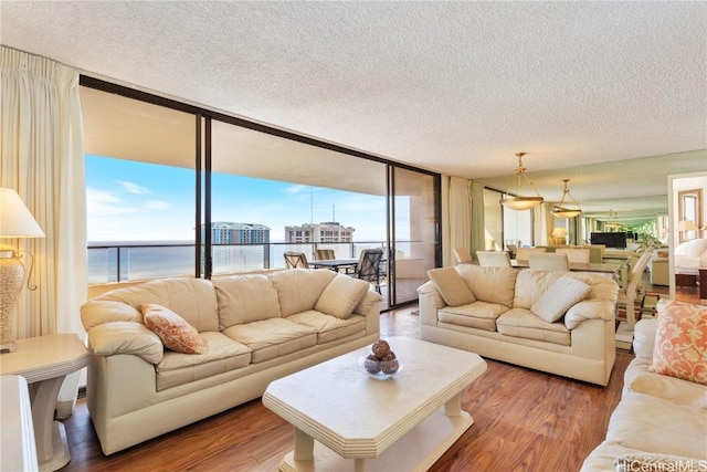 living room with a water view, a wall of windows, a textured ceiling, and hardwood / wood-style flooring