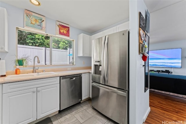 kitchen with white cabinets, appliances with stainless steel finishes, light tile patterned floors, and sink