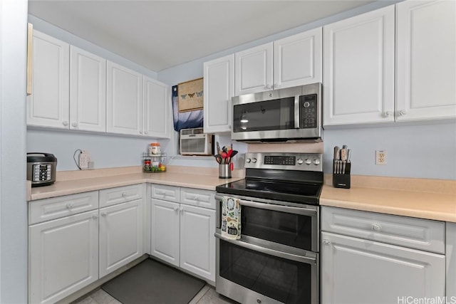 kitchen with appliances with stainless steel finishes, white cabinets, and an AC wall unit