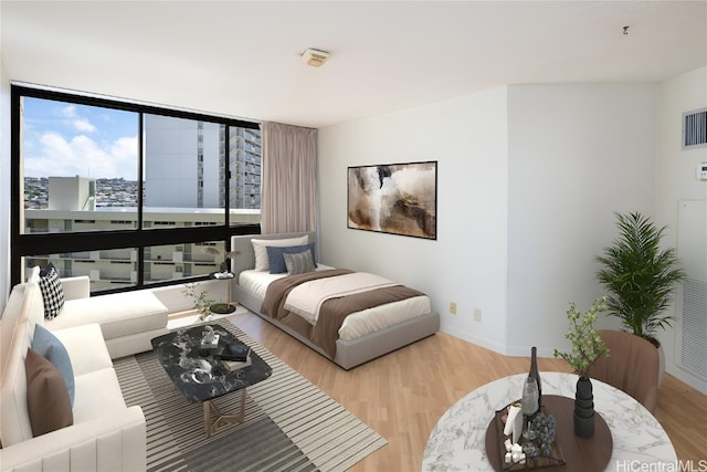 bedroom featuring expansive windows and light hardwood / wood-style flooring