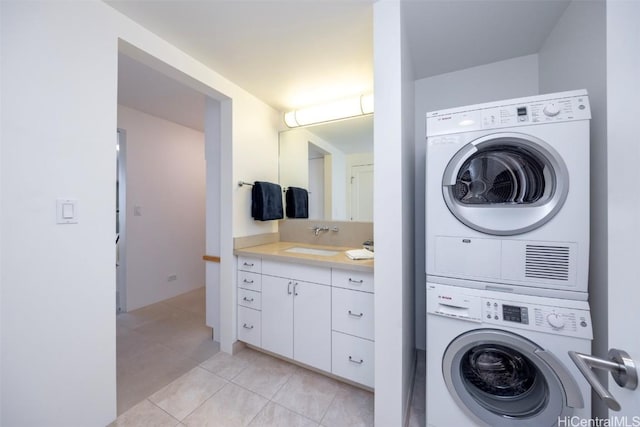 washroom with light tile patterned floors, stacked washer / drying machine, and sink