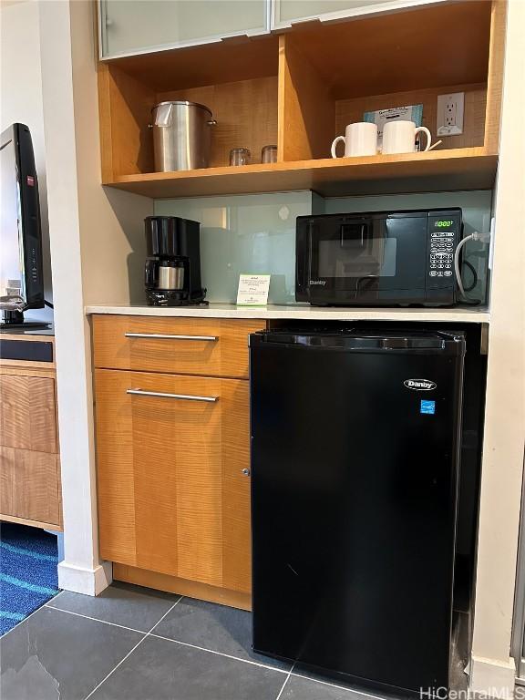 kitchen featuring open shelves, light countertops, dark tile patterned flooring, black microwave, and fridge