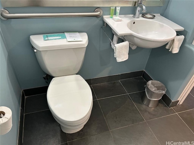 half bath featuring baseboards, a sink, toilet, and tile patterned floors