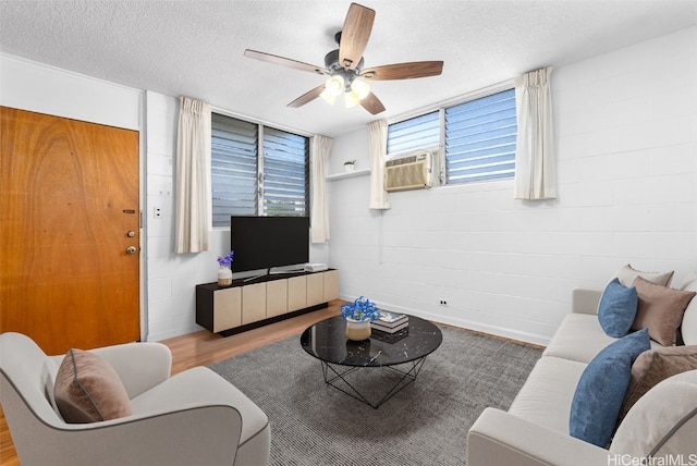 living room with a textured ceiling, ceiling fan, cooling unit, and wood-type flooring