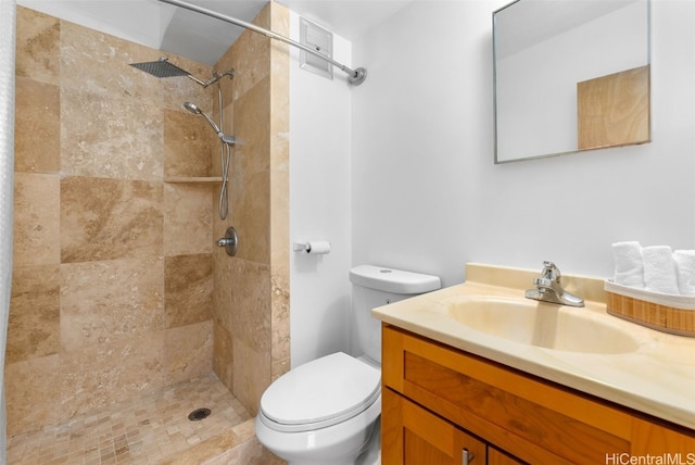 bathroom featuring toilet, vanity, and tiled shower