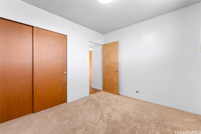 unfurnished bedroom featuring carpet, a closet, and a textured ceiling