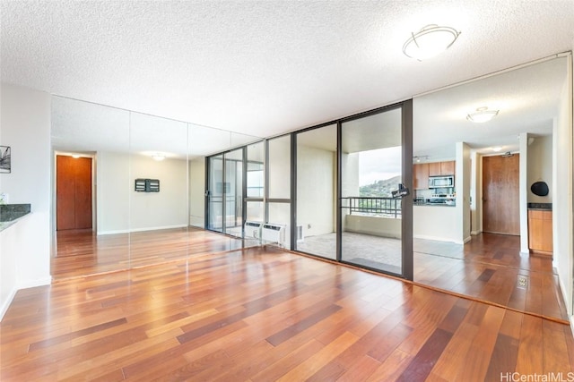 empty room with floor to ceiling windows, a textured ceiling, and wood-type flooring