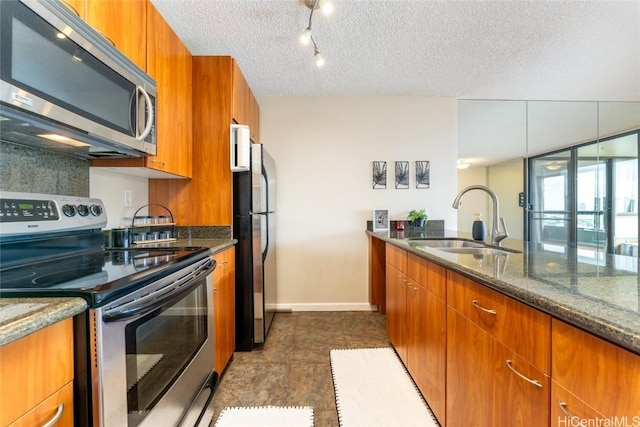 kitchen featuring sink, stainless steel appliances, dark stone countertops, and a textured ceiling