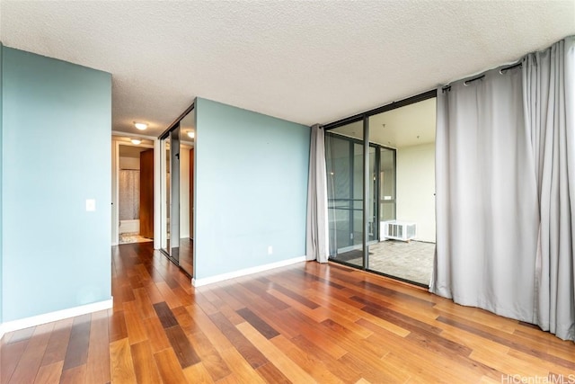 empty room featuring a textured ceiling, hardwood / wood-style floors, and expansive windows