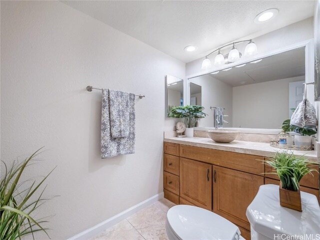 bathroom with toilet, vanity, and tile patterned floors