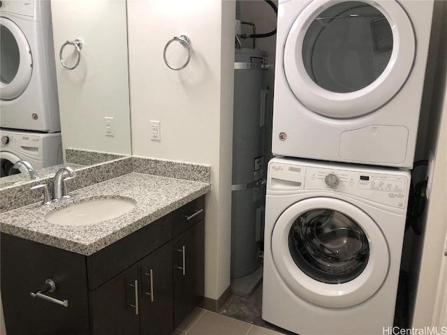 laundry area featuring strapped water heater, stacked washer and clothes dryer, dark tile patterned floors, and sink