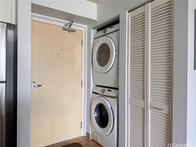 laundry room featuring dark wood-type flooring and stacked washer / drying machine