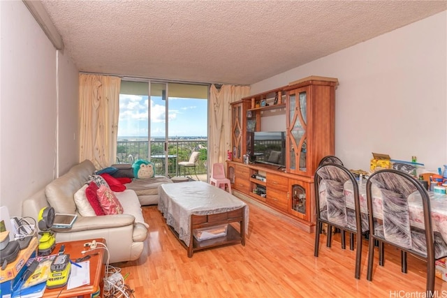 living room featuring floor to ceiling windows, a textured ceiling, and light hardwood / wood-style flooring