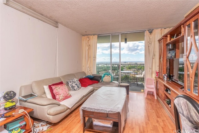 living room featuring a textured ceiling, floor to ceiling windows, and light hardwood / wood-style flooring