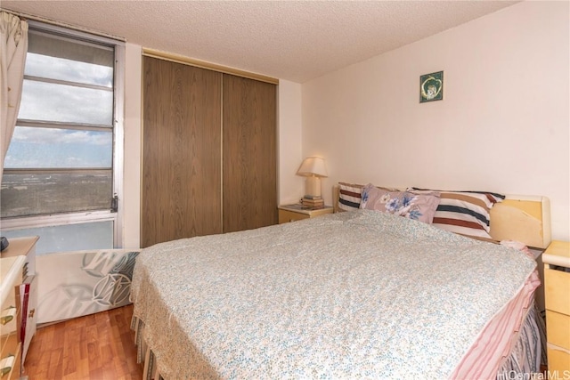 bedroom with a textured ceiling and light hardwood / wood-style flooring