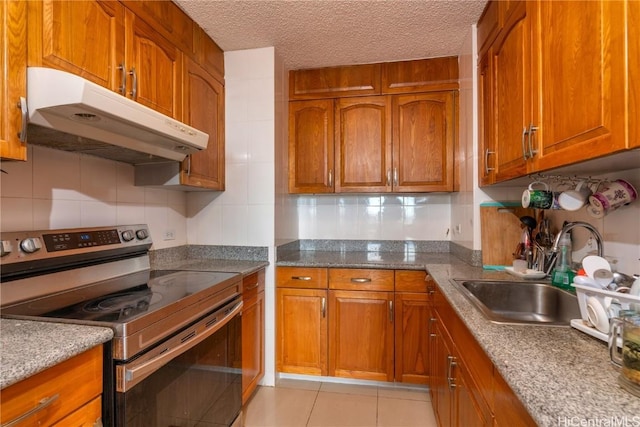 kitchen with electric range, light tile patterned floors, dark stone counters, a textured ceiling, and sink