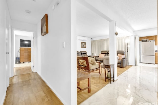 corridor with a textured ceiling and a wall mounted AC