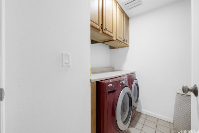 laundry area with washing machine and dryer, cabinets, and light tile patterned floors