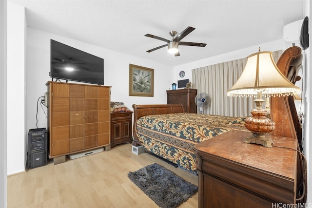 bedroom with ceiling fan, light hardwood / wood-style floors, and a textured ceiling