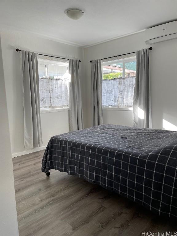 bedroom with a wall unit AC and wood-type flooring