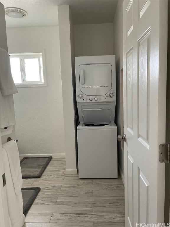 washroom featuring light hardwood / wood-style flooring and stacked washer / drying machine