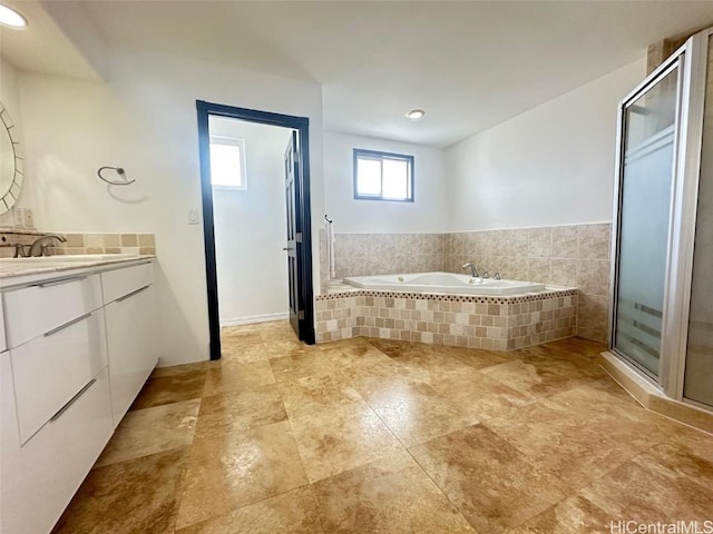 bathroom featuring a relaxing tiled tub and vanity