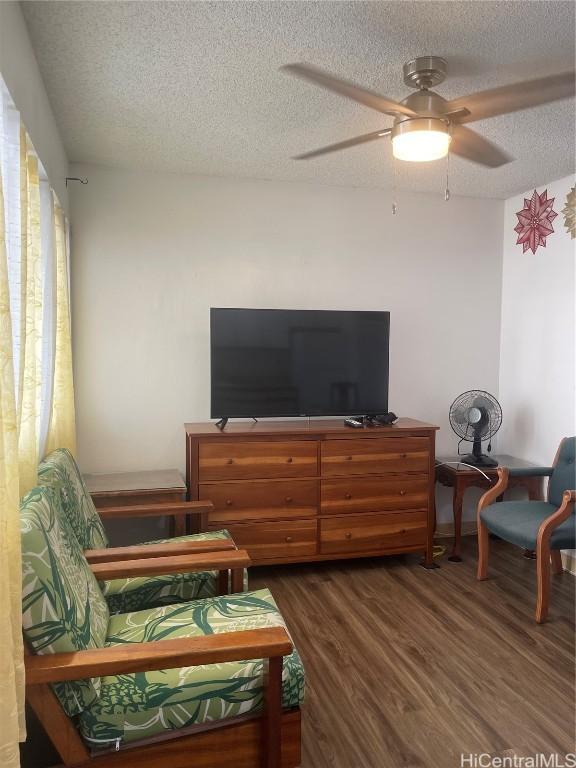 living area featuring a textured ceiling, ceiling fan, and dark hardwood / wood-style flooring