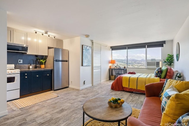 bedroom featuring light hardwood / wood-style floors, sink, cooling unit, and stainless steel fridge