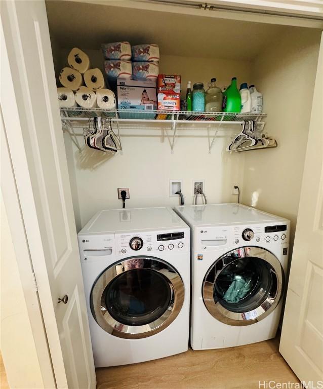 clothes washing area featuring washing machine and clothes dryer and light hardwood / wood-style flooring