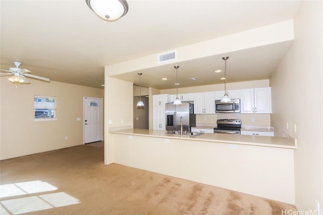 kitchen with sink, white cabinetry, decorative light fixtures, appliances with stainless steel finishes, and kitchen peninsula