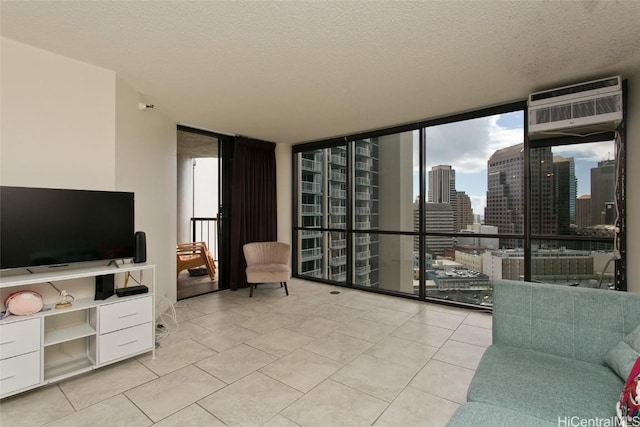 tiled living room with an AC wall unit, a wealth of natural light, a wall of windows, and a textured ceiling