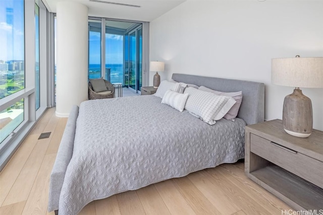 bedroom featuring access to outside, hardwood / wood-style flooring, and expansive windows