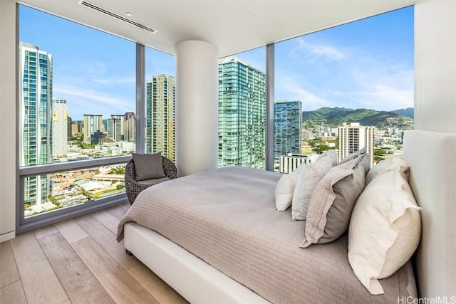 bedroom featuring light hardwood / wood-style floors, a wall of windows, and a mountain view