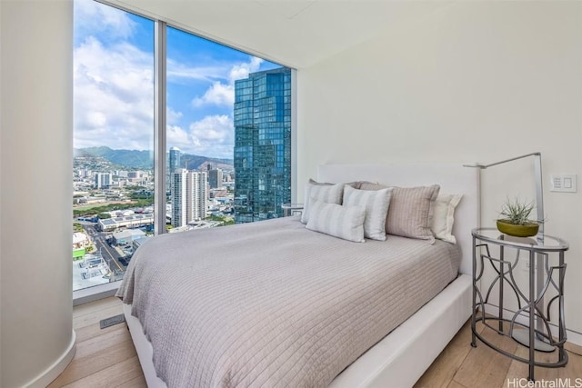 bedroom with floor to ceiling windows and light hardwood / wood-style floors