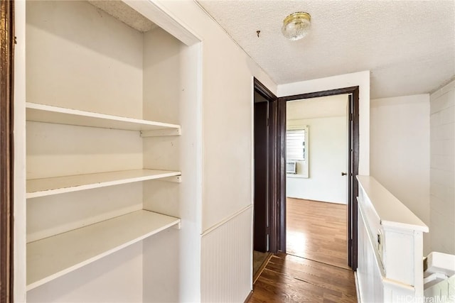 hallway with dark hardwood / wood-style floors, cooling unit, and a textured ceiling