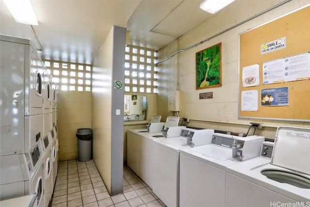 clothes washing area with separate washer and dryer, light tile patterned floors, and stacked washing maching and dryer