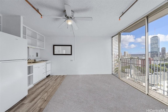 interior space with floor to ceiling windows, white appliances, white cabinets, and a textured ceiling