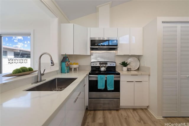 kitchen with sink, white cabinets, light wood-type flooring, and stainless steel appliances